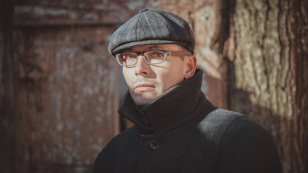 German male editor in his fifties wearing glasses and a tweed jacket, thoughtful expression